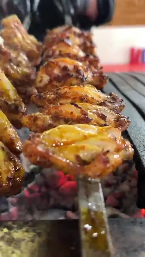 Kömür ateşinin üstünde şişe dizilmiş tavuk kanat