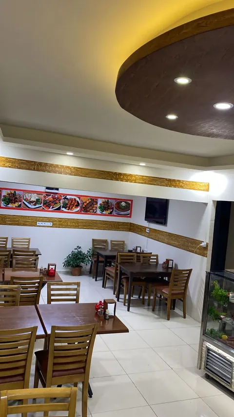 Salon, ahşap masalar ve duvarda altın rengi işletme yazısı