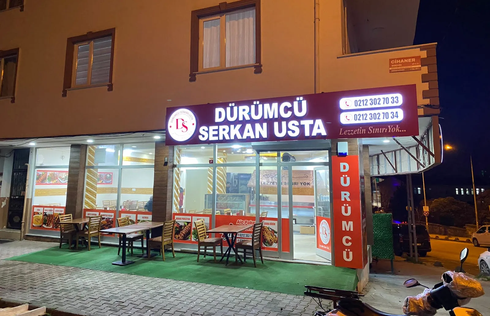Işıklı tabelası yanan dükkân cephesi, önünde kurulu masalar
